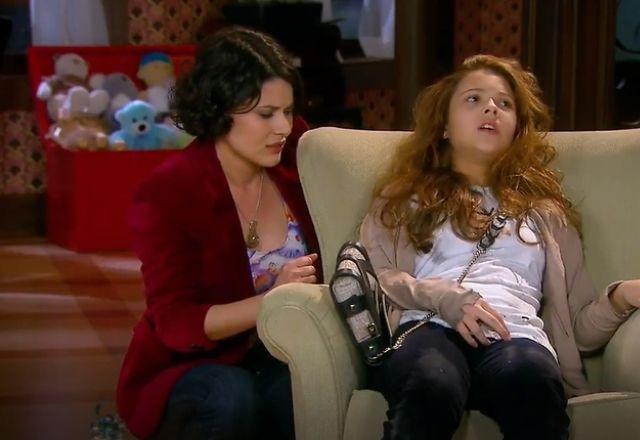 Marian sentada na cadeira da sala com Carol ao seu lado